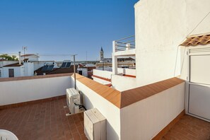 A rooftop terrace with a white wall, a brown-tiled floor, and a view of a distant tower. - Apartment "Casa Pereira" with Private Terrace, Balconies & Wi-Fi (Cartaya)