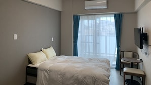 A hotel room with a bed, a chair, a TV, and a window with curtains. - Mr.KINJO in Kokusaidori (Naha)