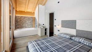 Una camera da letto con un letto, un bagno con una vasca e un muro in pietra.
