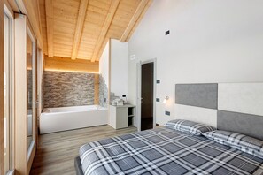 Ein Schlafzimmer mit Bett, ein Badezimmer mit Badewanne und einer Steinwand.