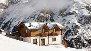 Un edificio in stile chalet con balconi, sullo sfondo di una montagna innevata.