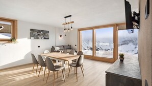 Una cucina moderna con zona pranzo, ampie finestre e vista su un paesaggio innevato.