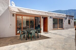 Ein Gebäude mit überdachter Terrasse, Schiebeglastüren und einer Satellitenschüssel.
