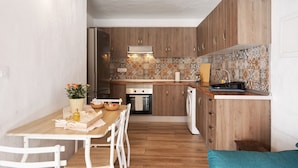 A compact kitchen with wooden cabinets, a tiled backsplash, and a dining area with a table and chairs. - Holiday Apartment "Casita Ana" with Mountain View & Private Terrace (El Paso)