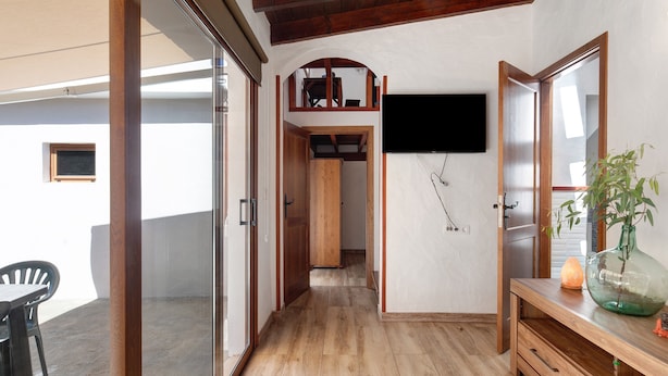 A hallway with wooden flooring, a TV mounted on the wall, a wooden bench, and a potted plant. - Holiday Apartment "Casita Ana" with Mountain View & Private Terrace (El Paso)