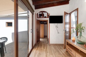 Ein Flur mit Holzboden, einem an der Wand montierten Fernseher, einer hölzernen Bank und einem Blumentopf.