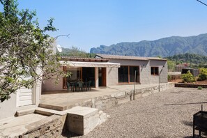 Ein zweistöckiges Haus mit Terrasse, kleinem Garten und Bergblick.