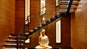 A staircase with a Buddha statue at the bottom, wooden walls, and modern lighting. - Wooden ECR Sea Resort (Marakkanam)