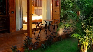 A wooden cabin with a balcony, a bed, and a table with chairs. - Wooden ECR Sea Resort (Marakkanam)