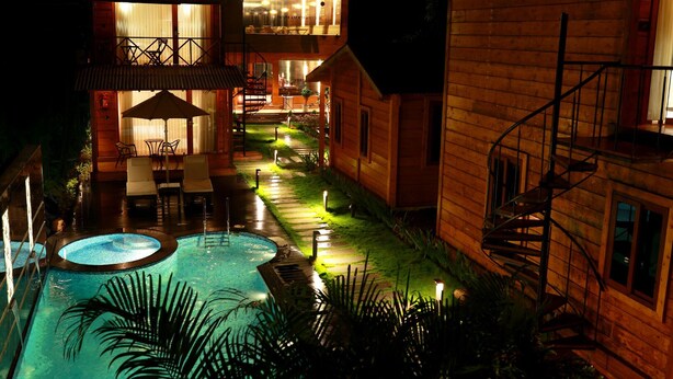 A nighttime view of a wooden house with a swimming pool, outdoor seating, and a staircase. - Wooden ECR Sea Resort (Marakkanam)