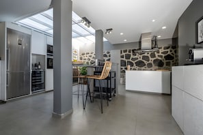 A modern kitchen with a skylight, a dining area with chairs, and a stone accent wall.