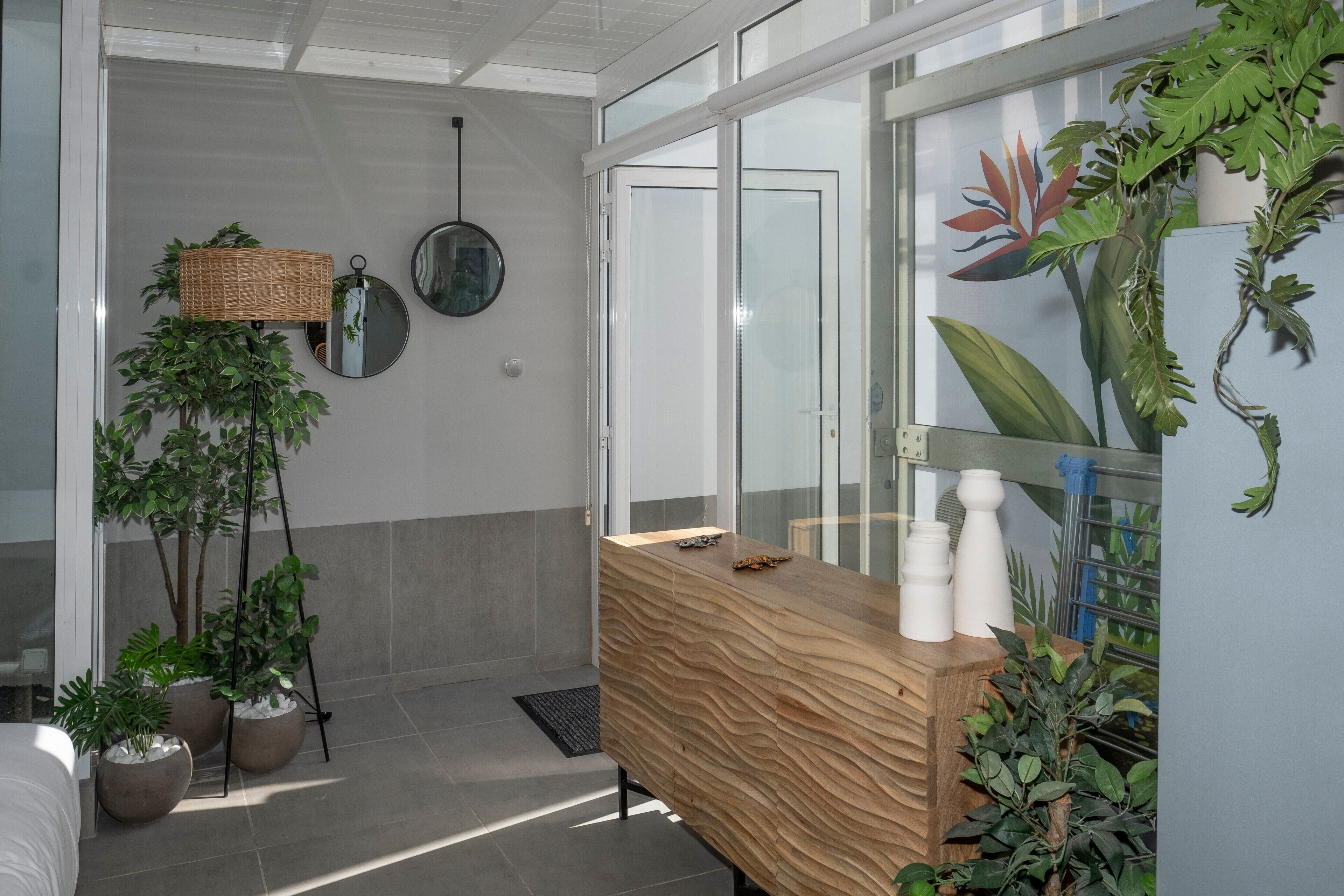 A modern bathroom with a wooden vanity, a mirror, and potted plants.