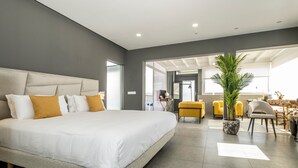 A modern hotel room with a large bed, a dining area with yellow chairs, and a potted plant. - Vacation Villa 'Casa Saidera ' with Private Pool, Wi-Fi and Air Conditioning (Playa Blanca)