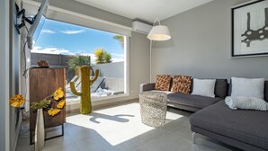 A modern living room with a grey sofa, a cactus, and a wooden cabinet. - Vacation Villa 'Casa Saidera ' with Private Pool, Wi-Fi and Air Conditioning (Playa Blanca)
