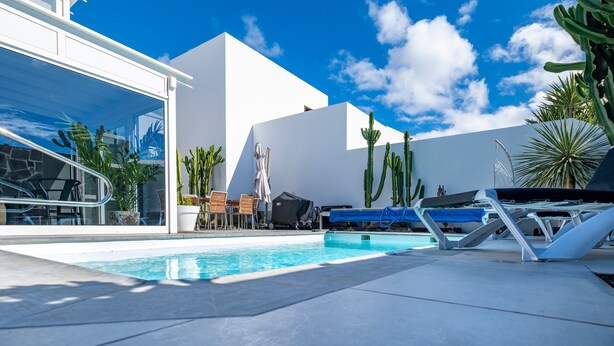 A pool area with lounge chairs, a table, and potted plants. - Vacation Villa 'Casa Saidera ' with Private Pool, Wi-Fi and Air Conditioning (Playa Blanca)