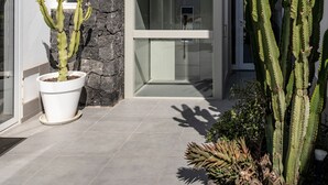 A modern building with a glass facade, a stone wall, and a cactus plant in the foreground. - Vacation Villa 'Casa Saidera ' with Private Pool, Wi-Fi and Air Conditioning (Playa Blanca)