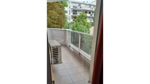 A balcony with a tiled floor, a white railing, and a view of a multi-story building with balconies. - Charming renovated T2 Nogent-sur-Marne: Mobility lease (Nogent-sur-Marne)