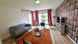 A modern living room with a sofa, chairs, a coffee table, and a bookshelf filled with books. - Charming renovated T2 Nogent-sur-Marne: Mobility lease (Nogent-sur-Marne)
