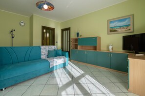Un salon avec un canapé, un téléviseur, des meubles et un tableau accroché au mur.