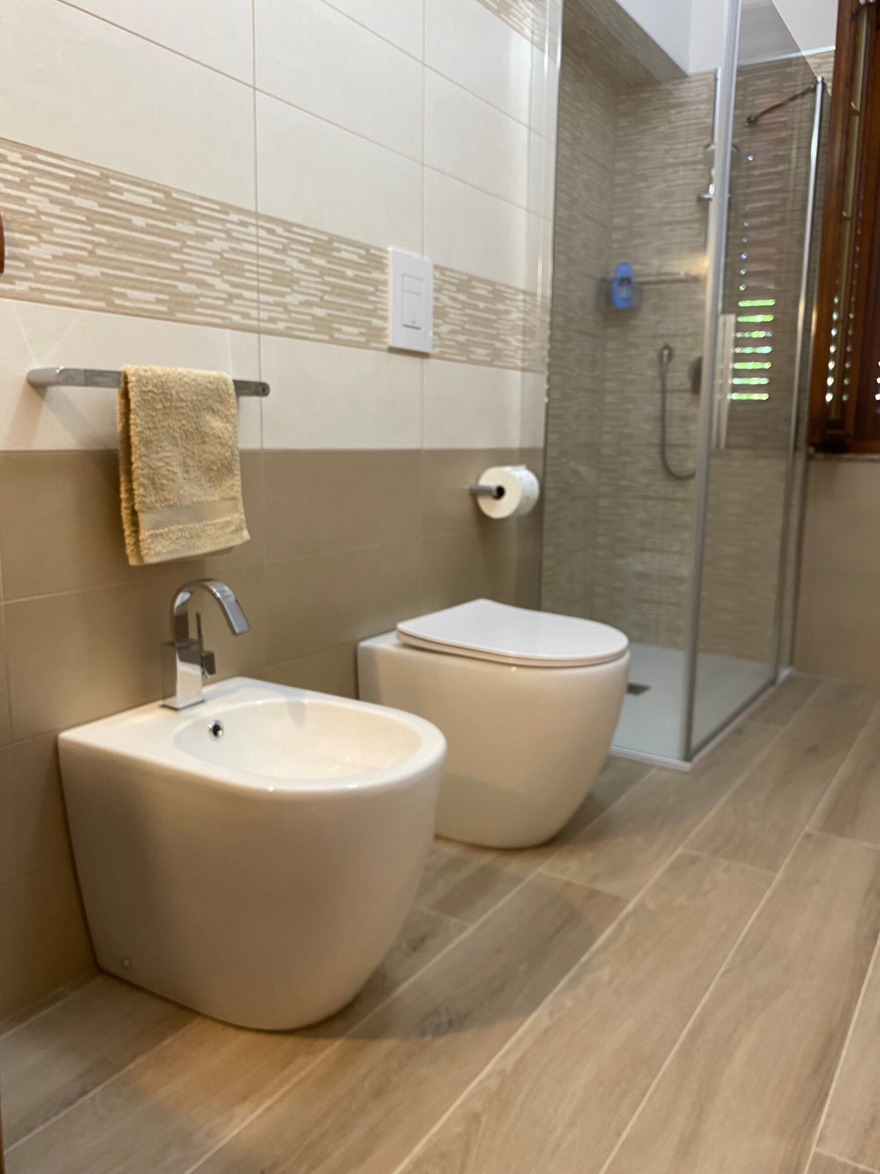 Et badeværelse med vask, toilet og glasvægs brusekabine.