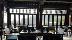 Un ristorante con arredi in legno, ampie finestre e vista sull'esterno.