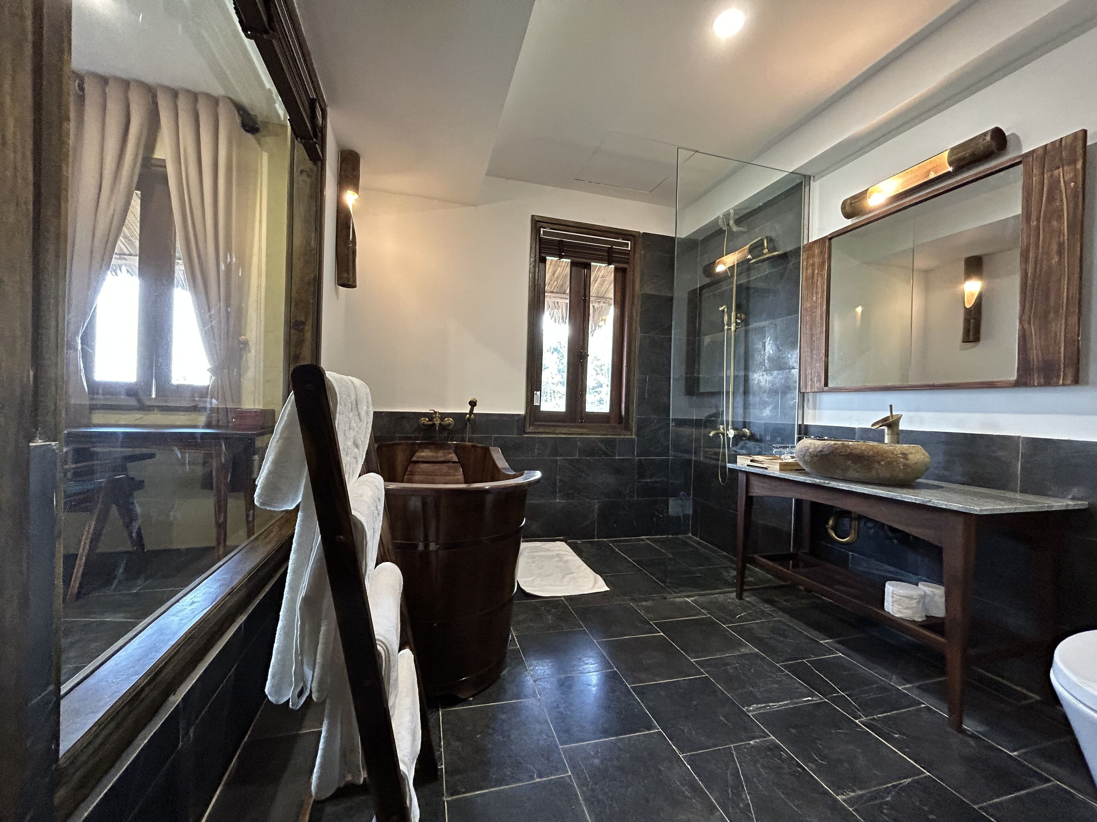 A modern bathroom with a bathtub, a glass-enclosed shower, and a large mirror above the sink.