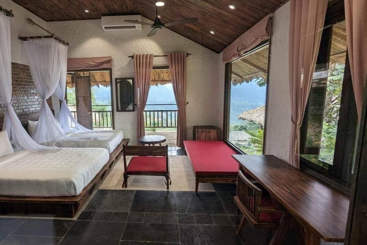 Une chambre avec deux lits, un banc, une télévision et un balcon avec vue.