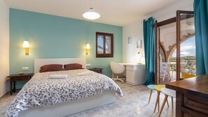 Ein Schlafzimmer mit Bett, Schreibtisch, Stuhl und Blick durch ein Fenster.