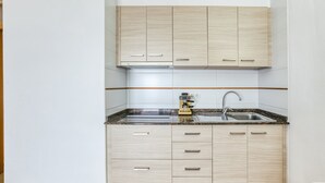 Een keuken met lichte houten kastjes, een granieten aanrecht, een geïntegreerde spoelbak en een koffieapparaat.