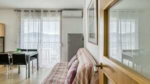 Een kamer met een bed, een eettafel met stoelen, een airconditioning en een raam met gordijnen.