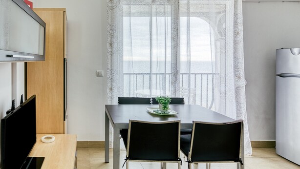 Een compacte, moderne keuken met een eettafel, stoelen en een televisie.