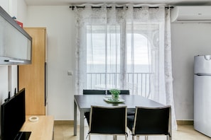A small, modern kitchen with a dining table, chairs, and a TV.