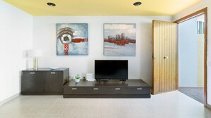 A modern living room with a flat-screen TV, dark wooden cabinet, and two abstract paintings on the wall.