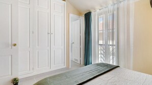A bedroom with a bed, a wardrobe, a door, and a window with curtains.
