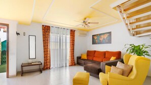 A living room with a sofa, ottoman, and a ceiling fan.