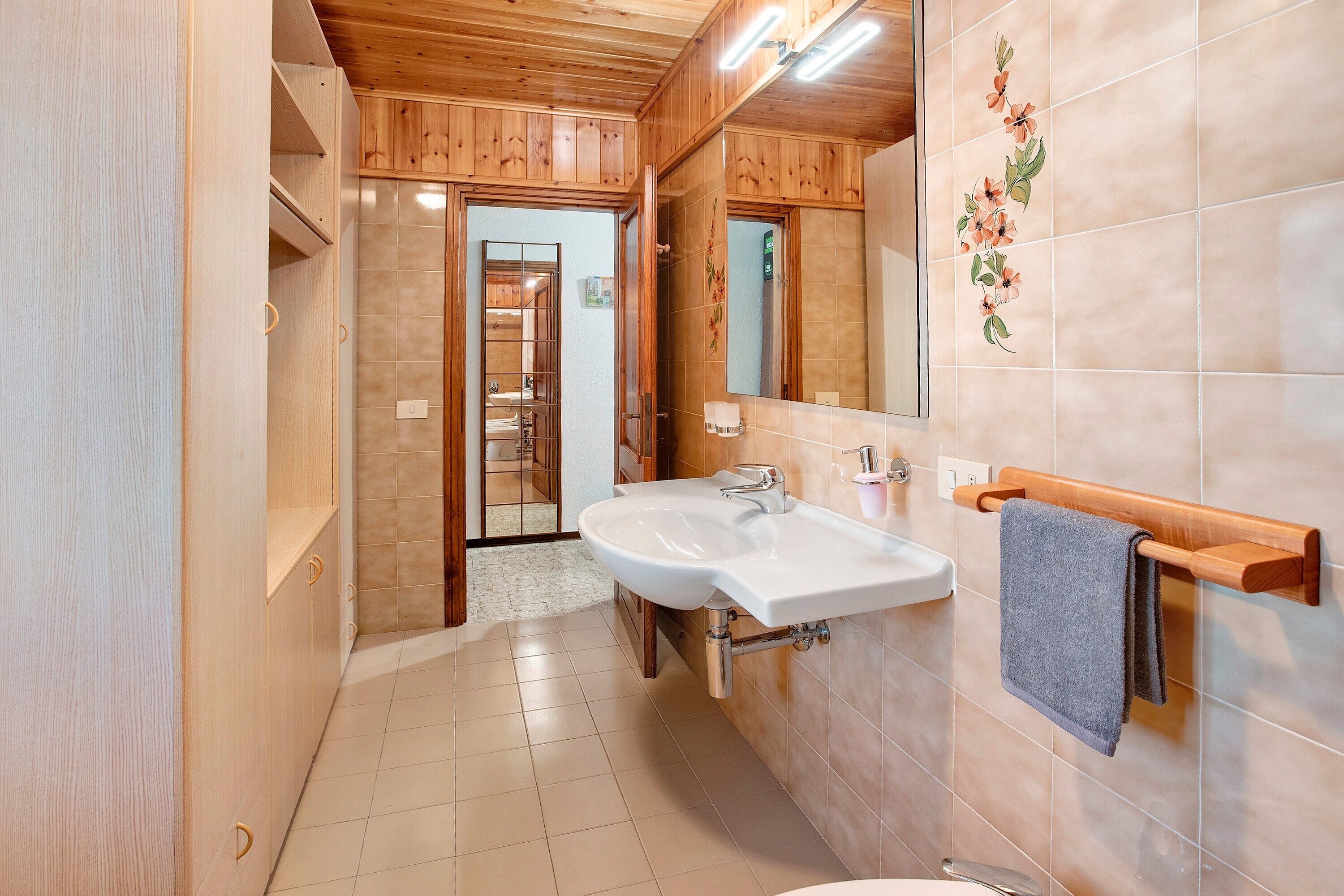 A bathroom with wooden cabinets, a double sink, and a mirror.