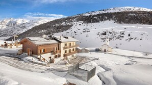 A snow-covered mountain landscape with a wooden building and a small church. - Apartment 'Presot' with Mountain View, Shared Garden & Wi-Fi (Livigno)