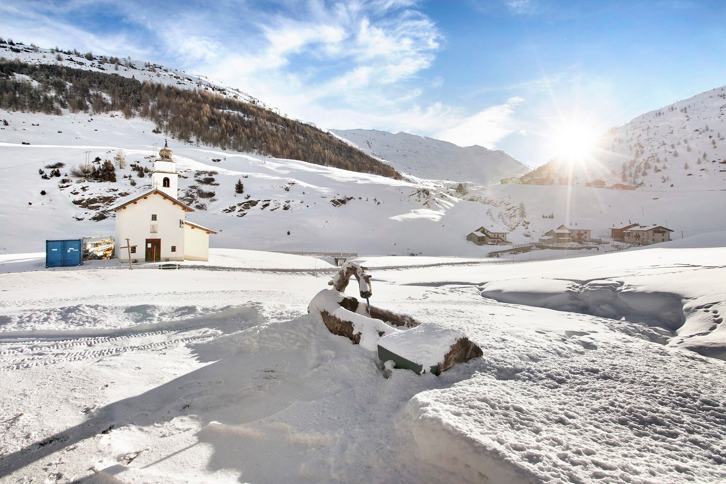 Un paysage enneigé avec un petit bâtiment, qui pourrait être une chapelle, et un bonhomme de neige.