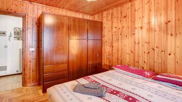 Une pièce aux murs lambrés, comprenant un lit, une armoire et une porte donnant sur une salle de bain.