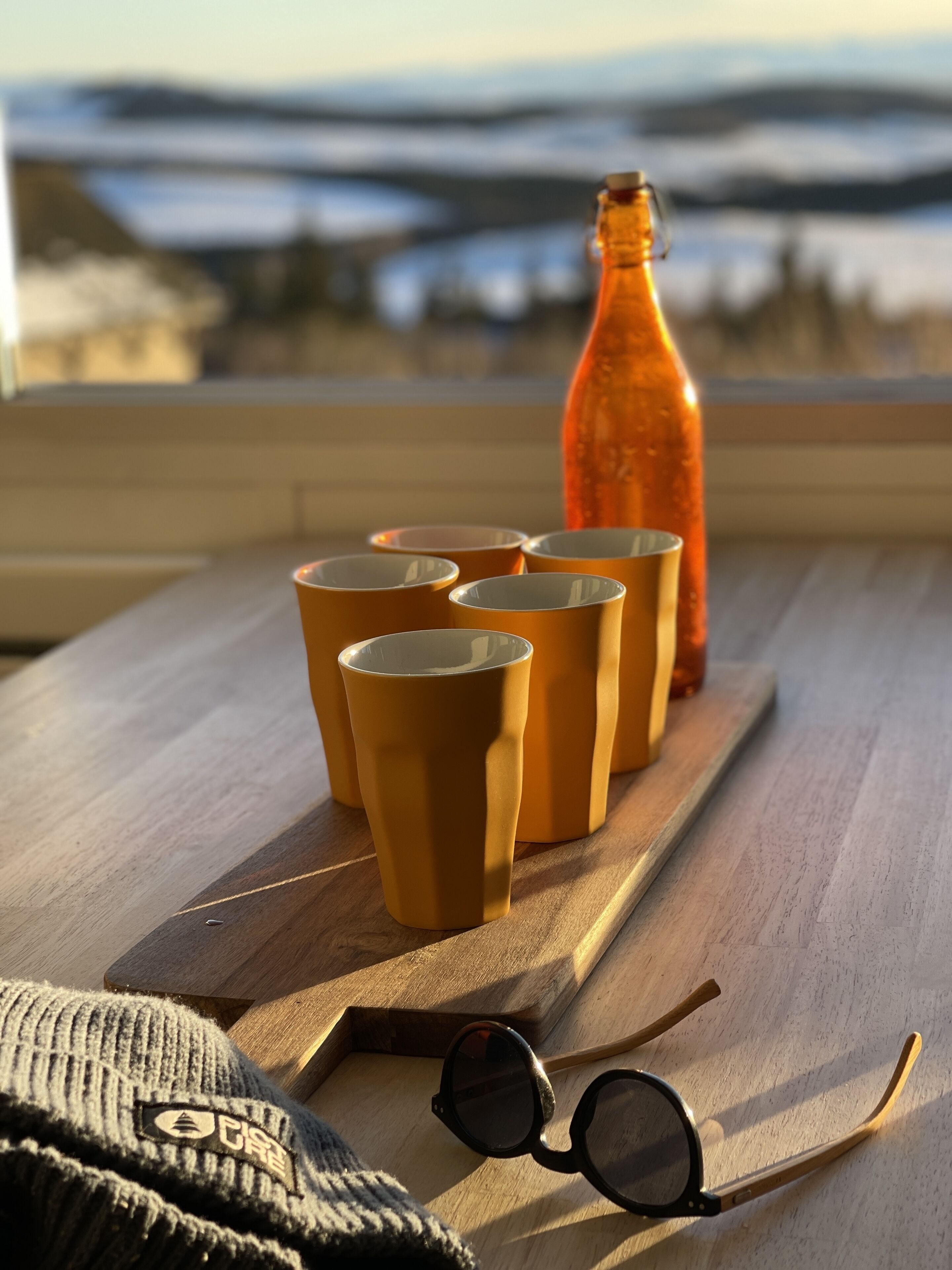 A wooden table with a bottle and several cups.