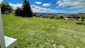 A grassy field with a house and trees in the background.