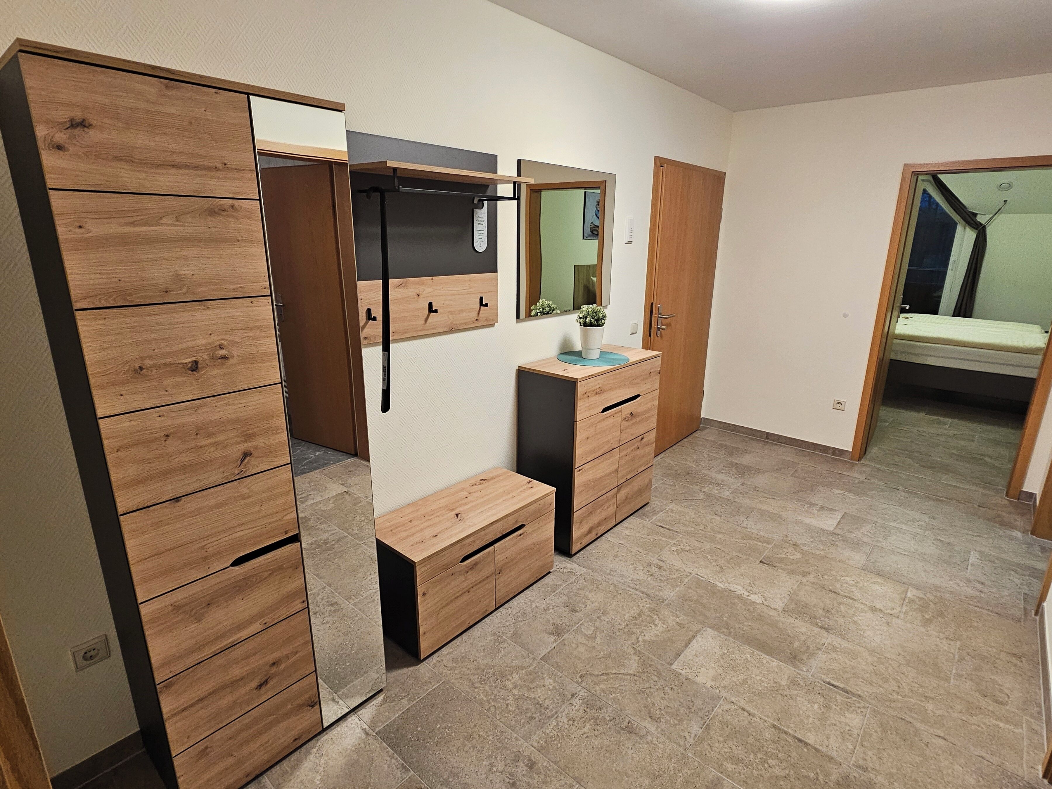 Un dormitorio con un armario de madera, una mesita de noche, un espejo y una cama.