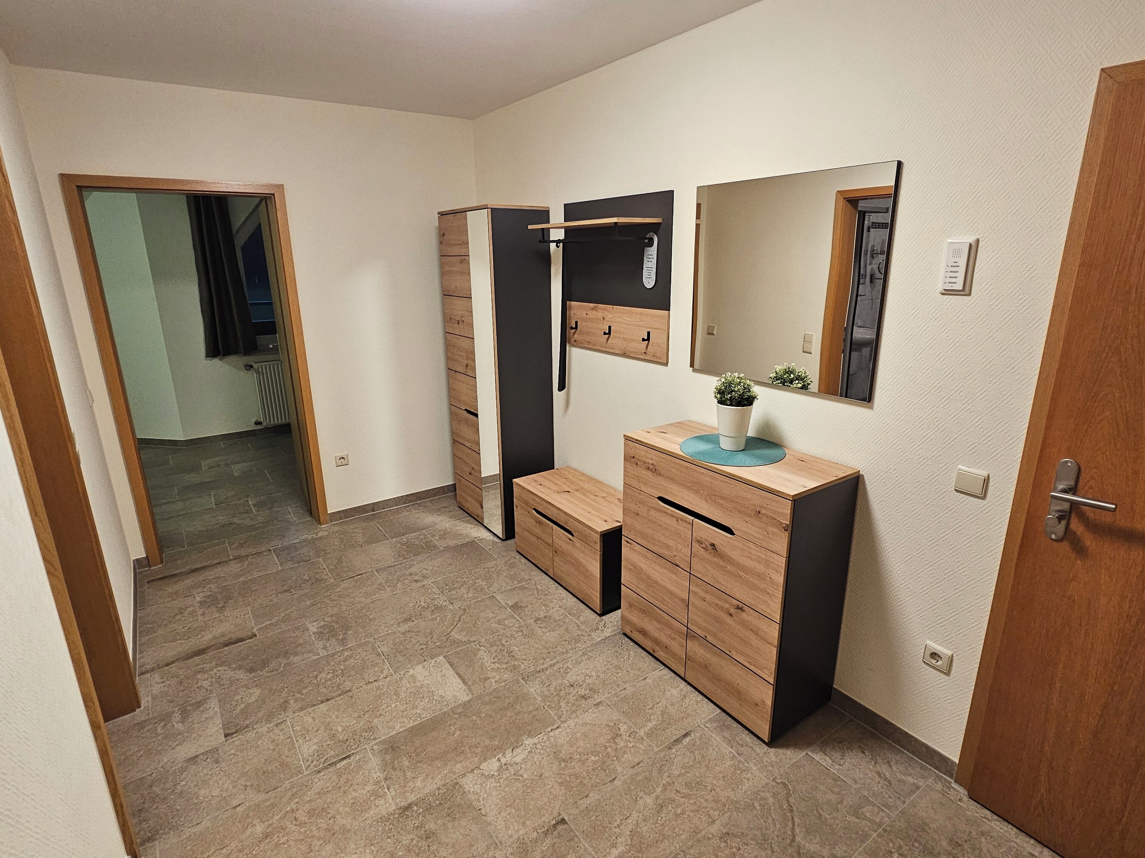 Un baño moderno con un tocador de madera, un espejo y una pequeña planta en maceta.