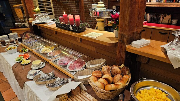 A buffet setup with various food items, including bread, pastries, and a variety of meats.