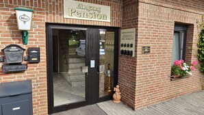 A brick building with a sign reading "Eingang Pension" and a mailbox.