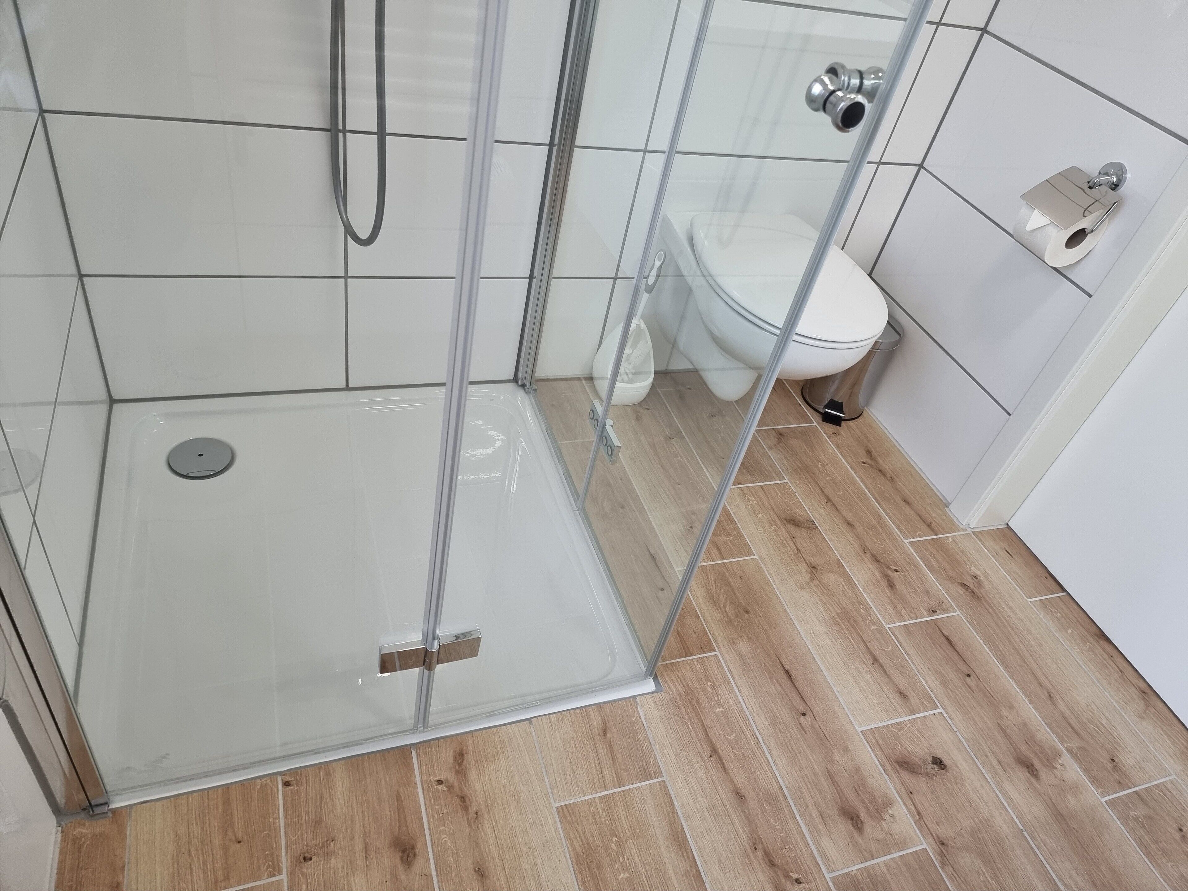 Ein Duschbereich mit Glastür, Toilette und Bidet.