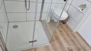Ein Duschbereich mit Glastür, Toilette und Bidet.