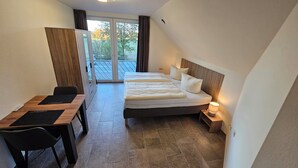 A bedroom with a double bed, a desk, and a chair.