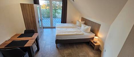 Un dormitorio con cama doble, un escritorio y una silla.