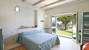 Ett sovrum med en säng, ett skrivbord, en stol och ett fönster med utsikt över omgivningen.